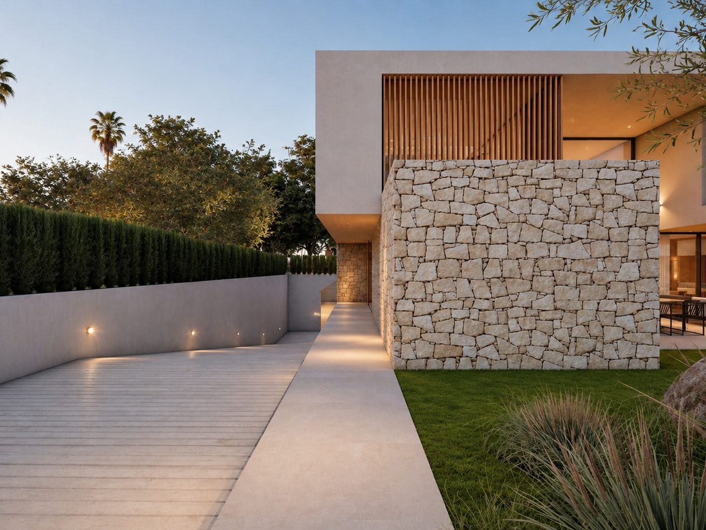 Casa Barenys — acceso y volumen de piedra iluminado al anochecer
